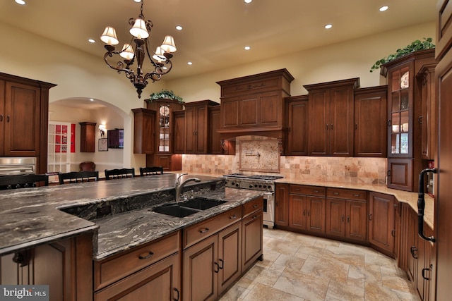 kitchen with decorative light fixtures, a notable chandelier, sink, stainless steel range, and a breakfast bar area