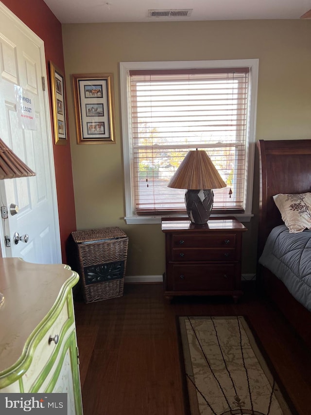 bedroom with dark wood-type flooring and multiple windows