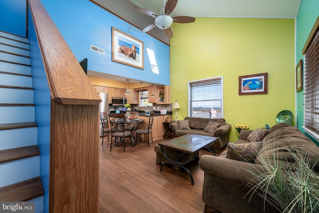 14211 Dukes Ave Unit 203, Ocean City, MD 21842 - living room with ceiling fan, stairway, wood finished floors, a towering ceiling, and healthy amount of natural light