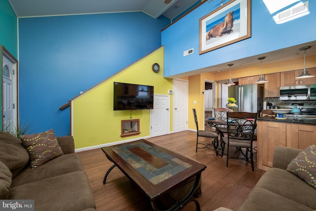 living room with dark hardwood / wood-style flooring, high vaulted ceiling, and beamed ceiling