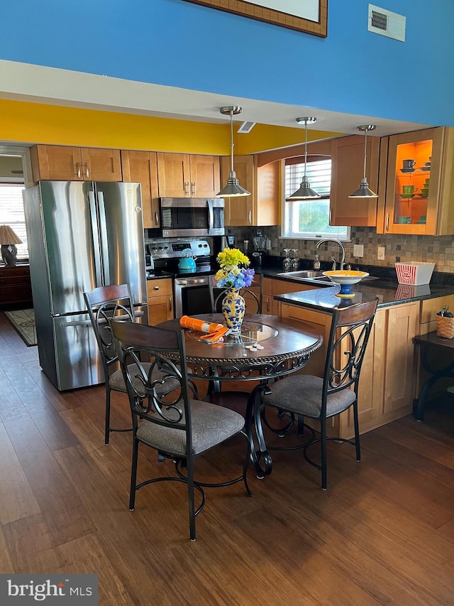 kitchen with decorative backsplash, stainless steel appliances, dark wood-type flooring, sink, and decorative light fixtures