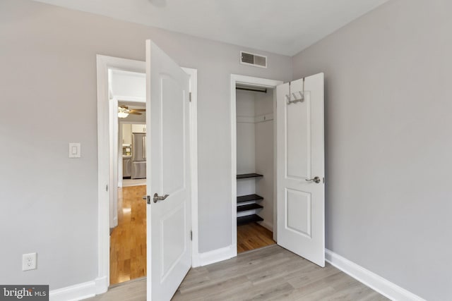 unfurnished bedroom with stainless steel fridge, baseboards, visible vents, and light wood-type flooring