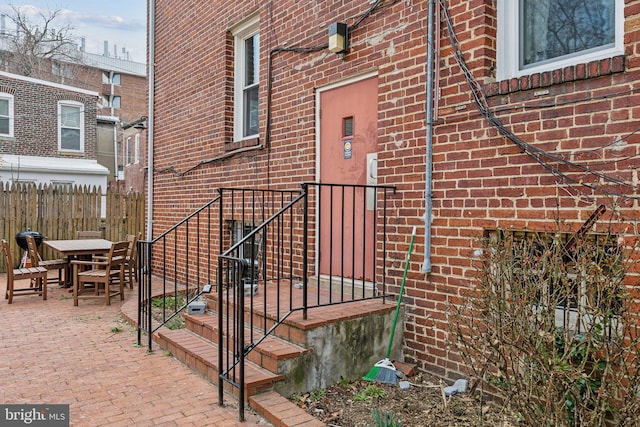 view of side of property with brick siding, outdoor dining space, a patio, and fence