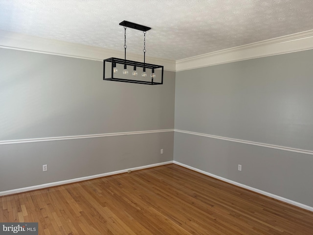 unfurnished dining area with crown molding, wood-type flooring, and a textured ceiling