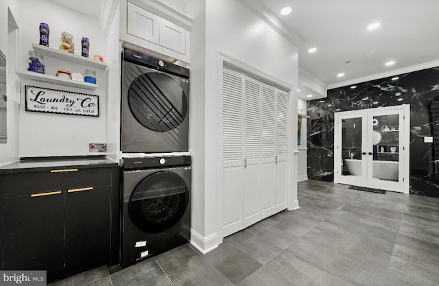 laundry area featuring cabinets, french doors, ornamental molding, and stacked washer / drying machine