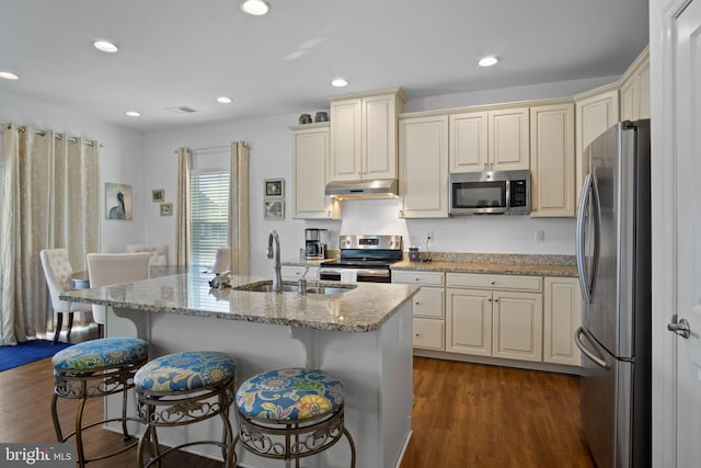 kitchen featuring appliances with stainless steel finishes, sink, an island with sink, a breakfast bar, and dark hardwood / wood-style floors