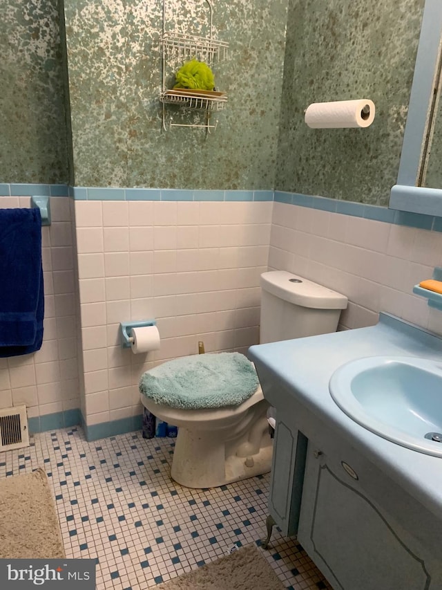 bathroom featuring tile patterned floors, vanity, toilet, and tile walls