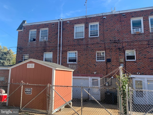 rear view of house with central AC unit and a storage unit