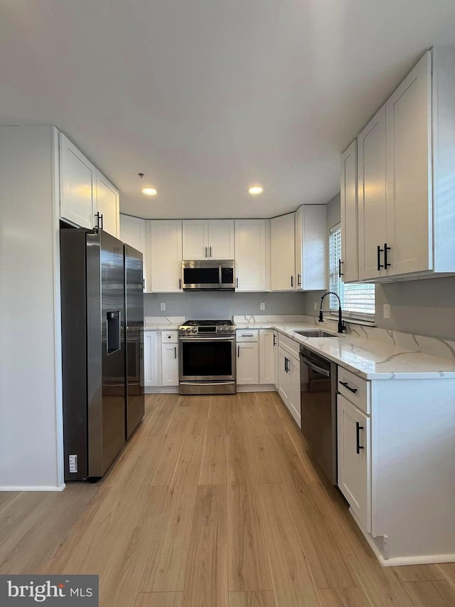 kitchen featuring sink, white cabinets, light hardwood / wood-style flooring, and appliances with stainless steel finishes