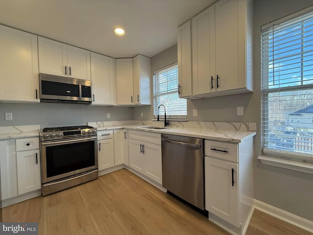 kitchen featuring white cabinetry, sink, stainless steel appliances, and light hardwood / wood-style floors