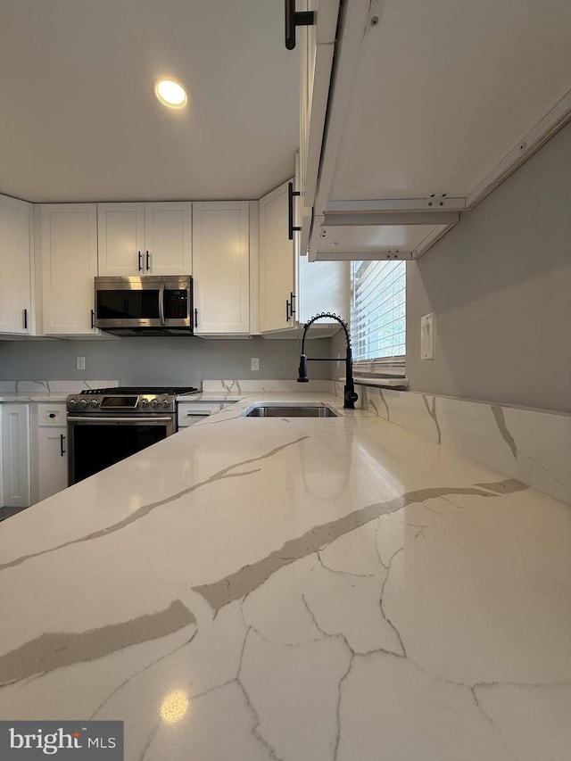 kitchen featuring light stone countertops, sink, white cabinets, and stainless steel appliances