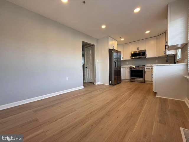 kitchen with white cabinets, stainless steel appliances, light hardwood / wood-style floors, and sink