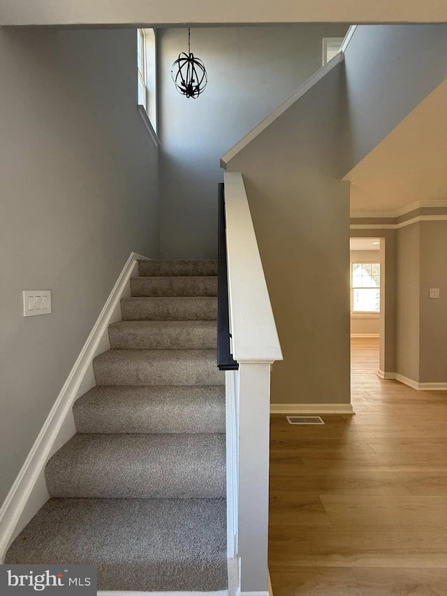 staircase featuring hardwood / wood-style flooring and a notable chandelier