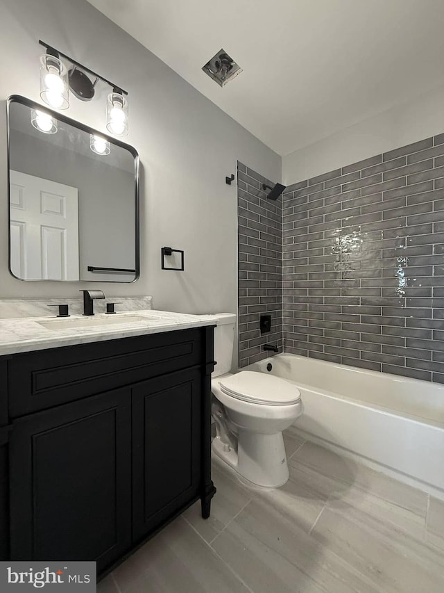 full bathroom featuring tile patterned flooring, vanity, toilet, and tiled shower / bath