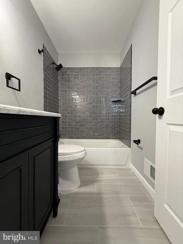 bathroom featuring tile patterned flooring, toilet, and tiled shower / bath