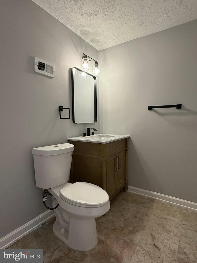 bathroom with vanity, a textured ceiling, and toilet