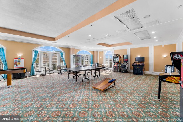 rec room featuring french doors, light carpet, ornamental molding, and a tray ceiling