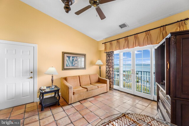 living room with a water view, ceiling fan, lofted ceiling, and light tile patterned floors