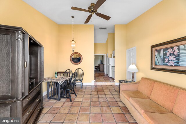 living room with ceiling fan and a towering ceiling