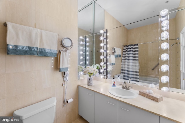 bathroom with toilet, a shower with shower curtain, vanity, and tile walls