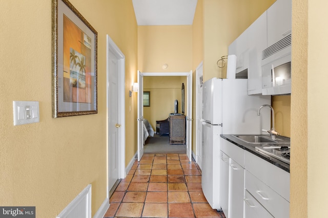 kitchen featuring white cabinetry, sink, and white appliances