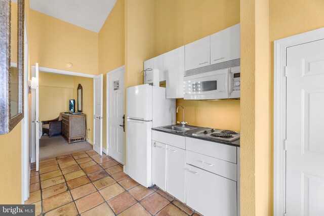 kitchen featuring a towering ceiling, sink, white cabinets, and white appliances