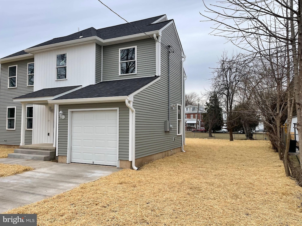 view of side of home featuring driveway, a garage, and roof with shingles