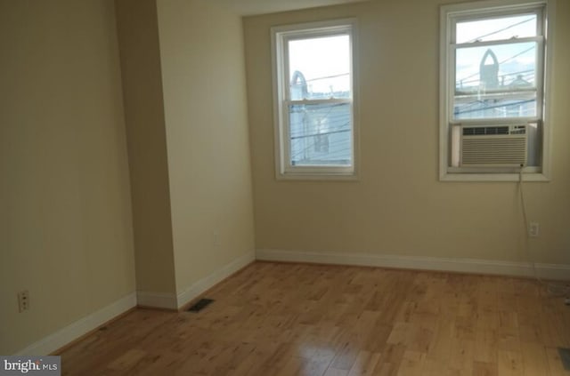 empty room featuring cooling unit and light hardwood / wood-style floors