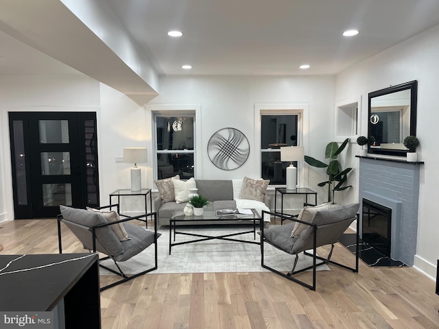 living room with a brick fireplace and light hardwood / wood-style flooring