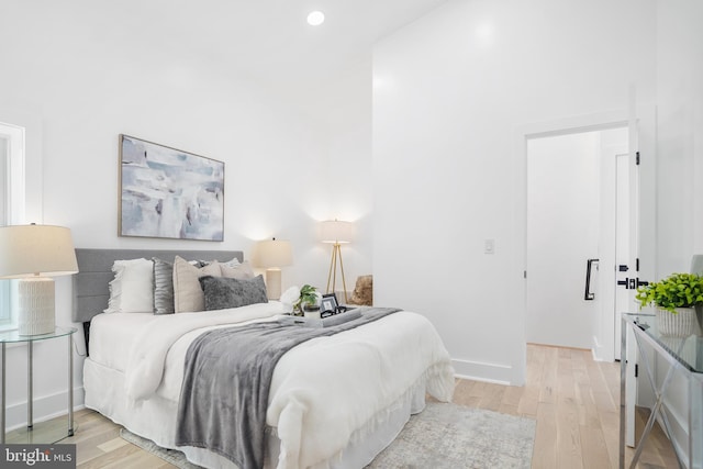 bedroom with a high ceiling and light hardwood / wood-style flooring