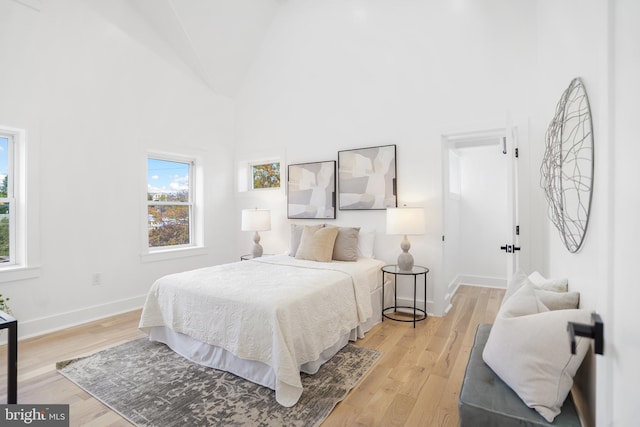 bedroom featuring high vaulted ceiling and light hardwood / wood-style flooring