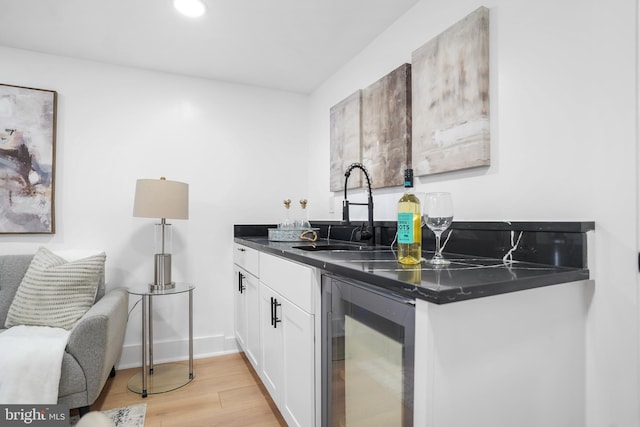 kitchen with sink, white cabinetry, beverage cooler, and light hardwood / wood-style flooring