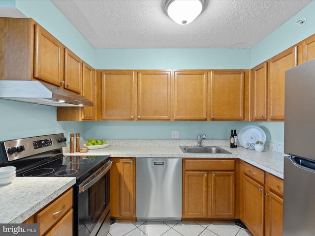 kitchen with stainless steel appliances, a textured ceiling, sink, and light tile patterned floors