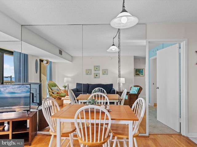 dining area with hardwood / wood-style floors and a textured ceiling