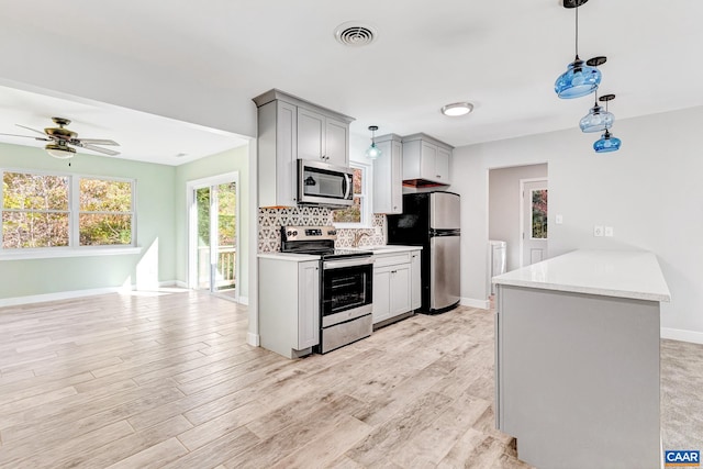 kitchen featuring hanging light fixtures, gray cabinets, appliances with stainless steel finishes, light hardwood / wood-style floors, and ceiling fan