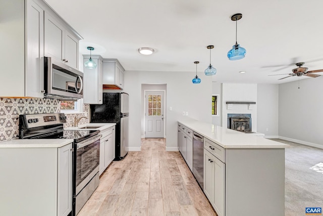 kitchen with hanging light fixtures, ceiling fan, sink, light hardwood / wood-style floors, and stainless steel appliances