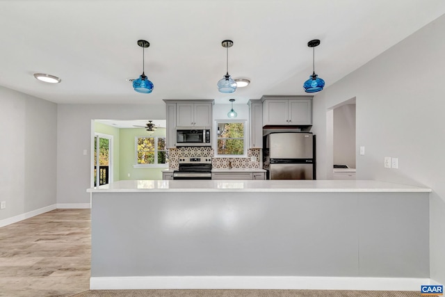 kitchen with backsplash, ceiling fan, stainless steel appliances, gray cabinets, and decorative light fixtures