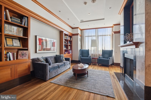 living room featuring built in features, a tray ceiling, hardwood / wood-style flooring, and a fireplace