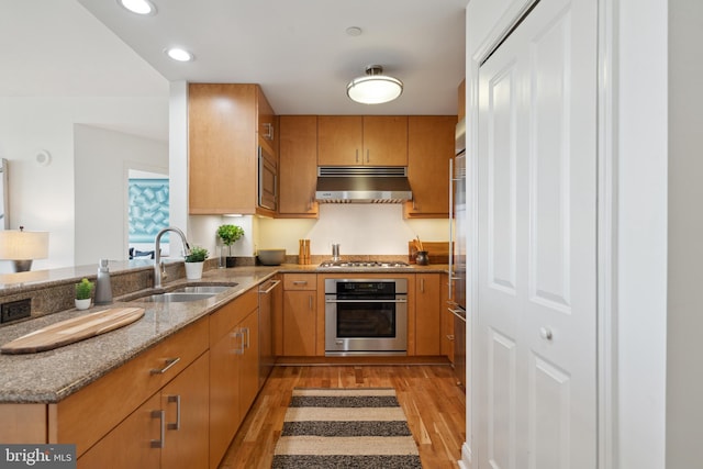 kitchen featuring light hardwood / wood-style floors, stone countertops, sink, kitchen peninsula, and appliances with stainless steel finishes