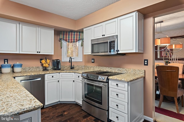 kitchen with light stone countertops, stainless steel appliances, dark hardwood / wood-style flooring, a textured ceiling, and white cabinets