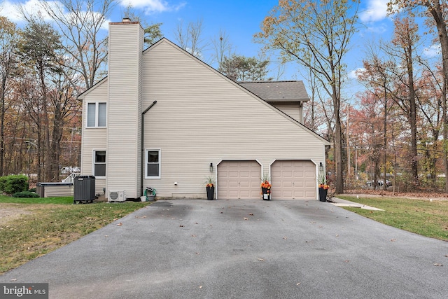 view of side of property with cooling unit, a garage, and a yard