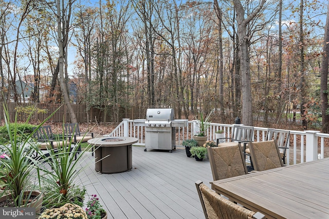 wooden terrace featuring area for grilling and an outdoor fire pit