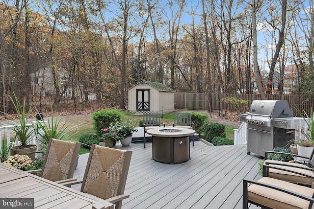 deck with a grill, a fire pit, and a storage unit