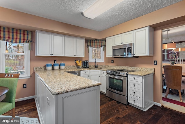 kitchen featuring a textured ceiling, dark hardwood / wood-style floors, white cabinetry, and stainless steel appliances