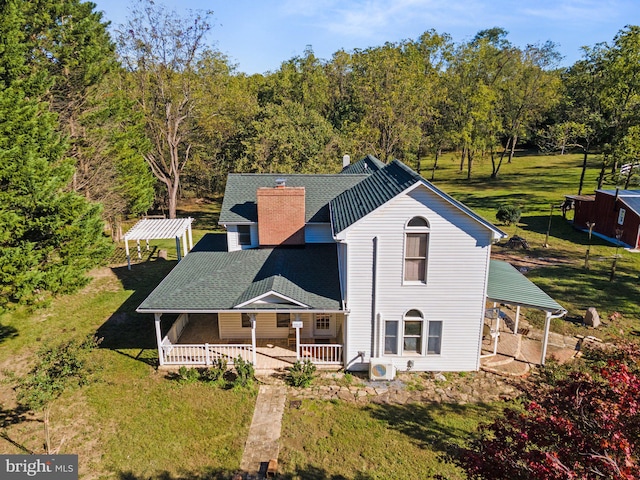 back of property with ac unit, a yard, and covered porch