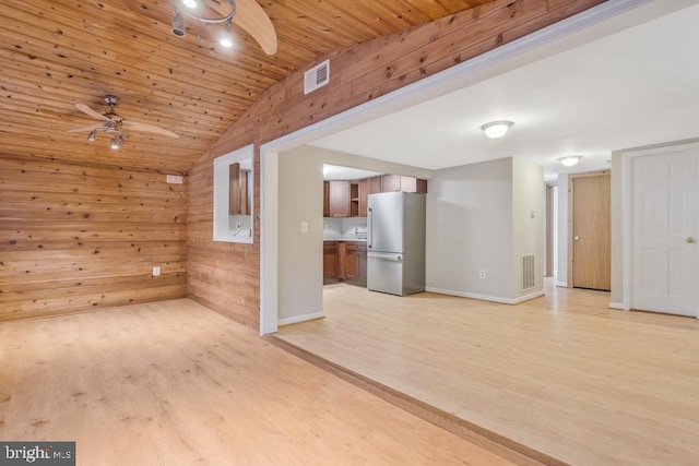 spare room with wooden walls, light wood-type flooring, vaulted ceiling, and wood ceiling