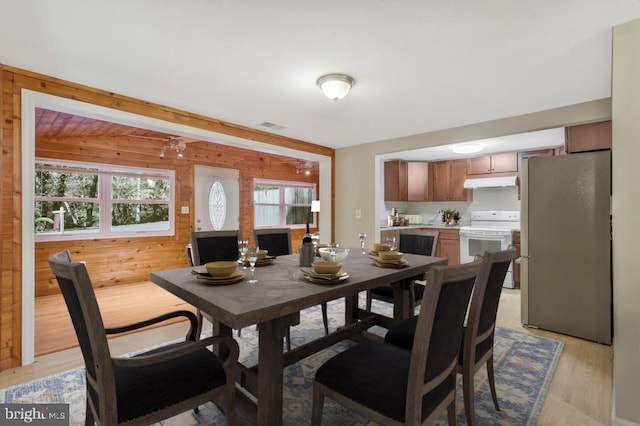 dining area with light hardwood / wood-style flooring and wooden walls