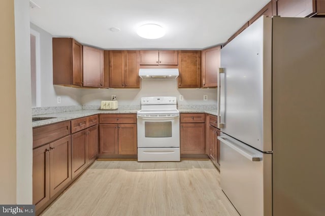 kitchen with stainless steel refrigerator, sink, light stone countertops, white electric stove, and light hardwood / wood-style flooring