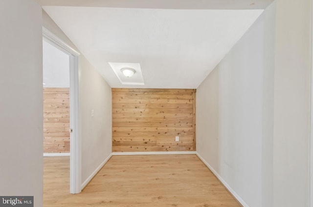 interior space with hardwood / wood-style floors, wood walls, and a skylight