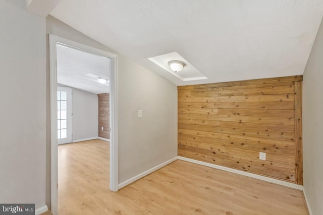 additional living space featuring wooden walls, vaulted ceiling, and wood-type flooring